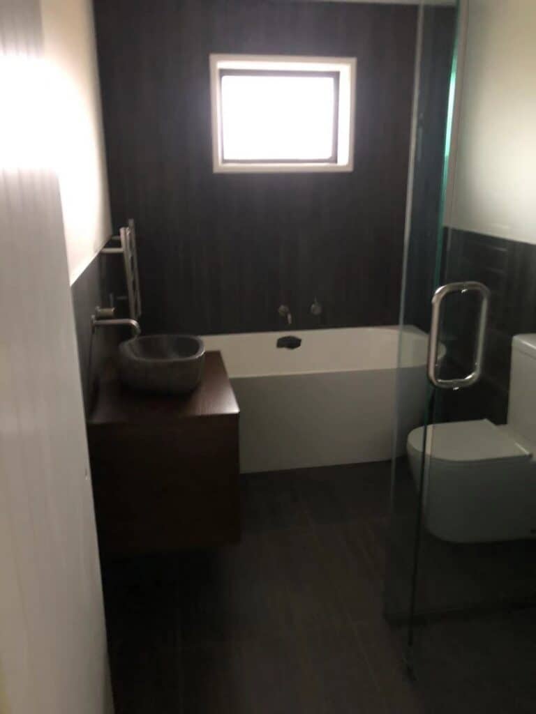 A clean, modern bathroom with a bathtub, glass shower, and sleek fixtures, following professional cleaning.