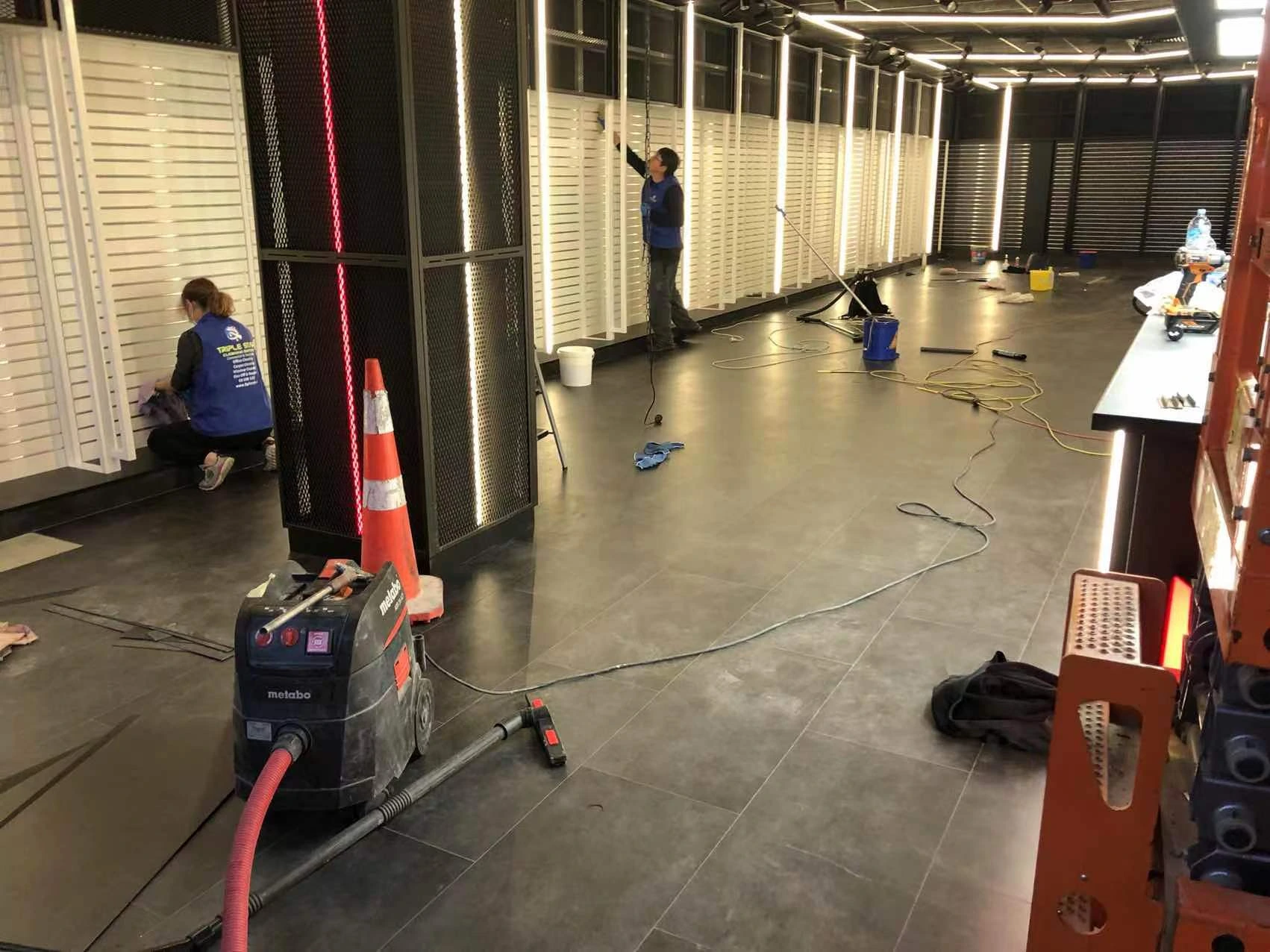 A team of professional cleaners performing post-construction cleaning in a commercial space, using industrial cleaning equipment and tools.