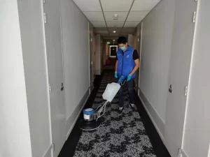 Professional carpet cleaning technician using an encapsulation carpet cleaning machine in a commercial hallway.