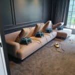 Professional upholstery cleaning with industrial air dryers placed on a large beige sofa in a modern living room.