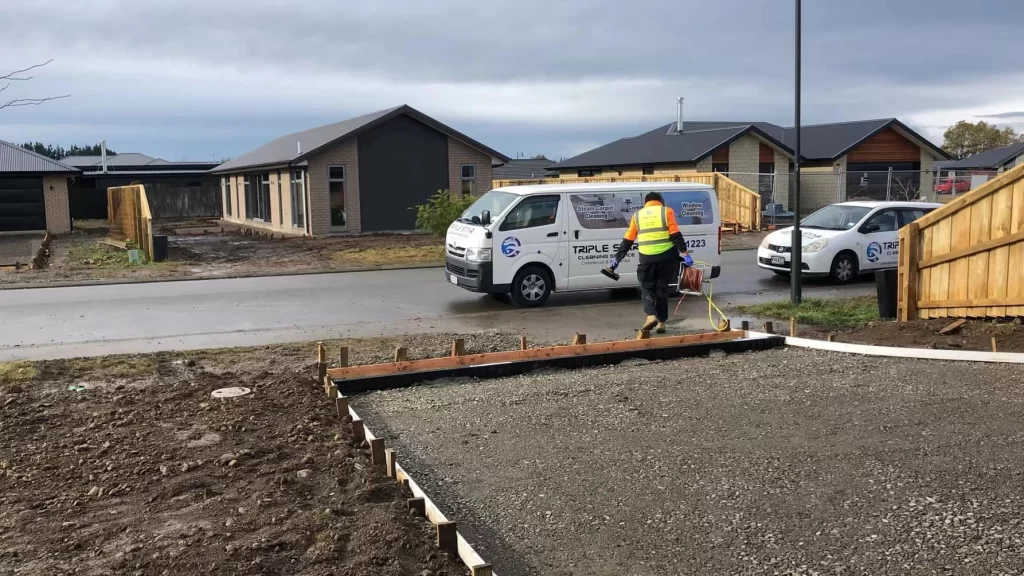 Professional cleaner performing Builders Cleaning cleaning on a new residential property site with Triple Star Commercial Cleaning vehicles nearby.