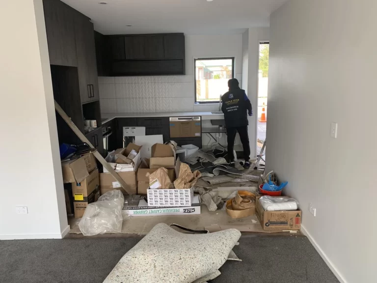 Professional cleaner performing post-construction cleaning in a kitchen filled with construction debris and materials.