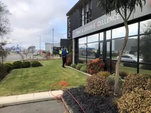 Professional window cleaners working on exterior glass windows of a commercial building using specialized equipment.