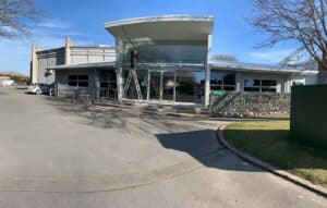 Professional window cleaner on a ladder cleaning large commercial windows of a modern building.