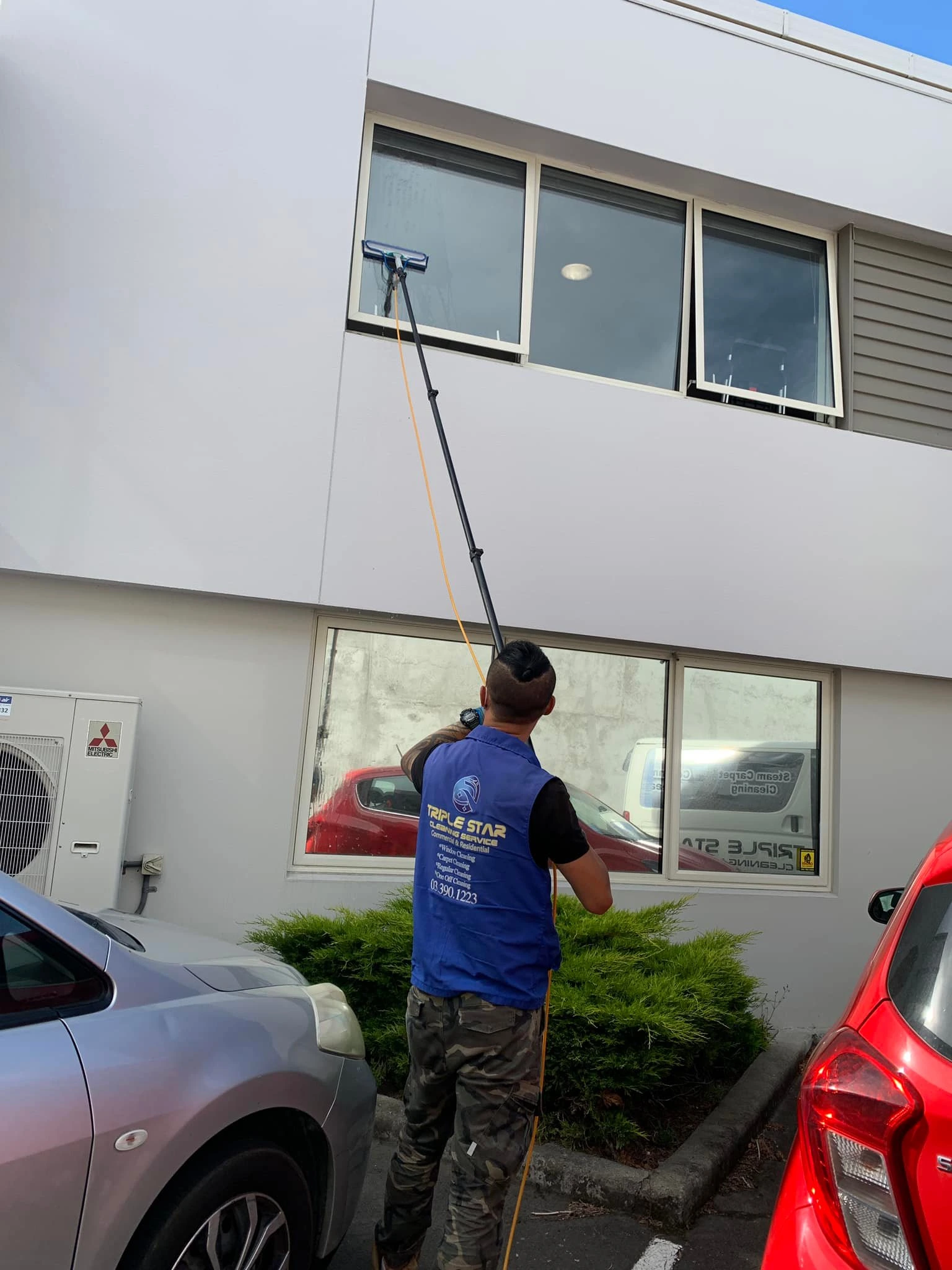 Triple Star Commercial Cleaning staff using a telescopic pole to wash office and retail windows in Christchurch and Auckland.