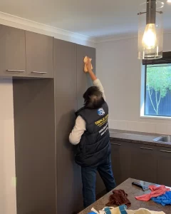 Triple Star Commercial Cleaning team member wiping down kitchen cabinets as part of an end-of-lease cleaning service in Auckland and Christchurch.