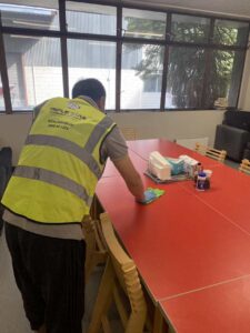 Triple Star Commercial Cleaning staff disinfecting an office meeting table in Christchurch and Auckland, ensuring a spotless workspace.